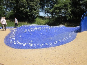 Installation aus blauen Steinen und blanken Blechbüchsen